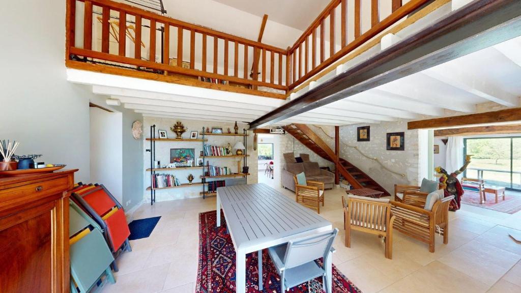 ein Wohnzimmer mit Tisch und Treppe in der Unterkunft Maison de la Gentinière in Mareuil-sur-Cher