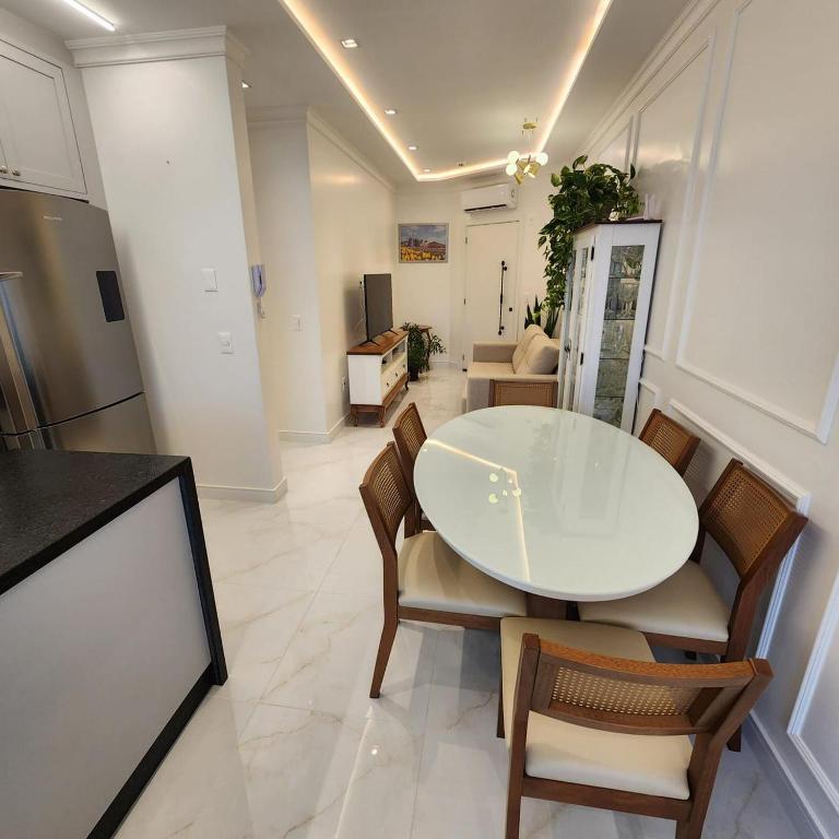Un comedor con una mesa y sillas blancas. en Doce lar, en Itapema
