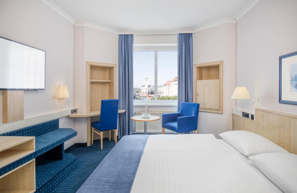 ein Hotelzimmer mit einem Bett und einem Tisch und Stühlen in der Unterkunft Hotel Erfurt City Center by Leonardo Hotels in Erfurt