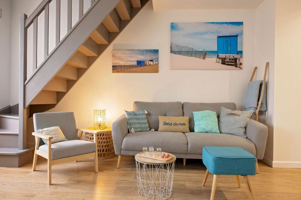 a living room with a couch and a staircase at Le Presbytère des Baraques à Blériot-Plage in Sangatte