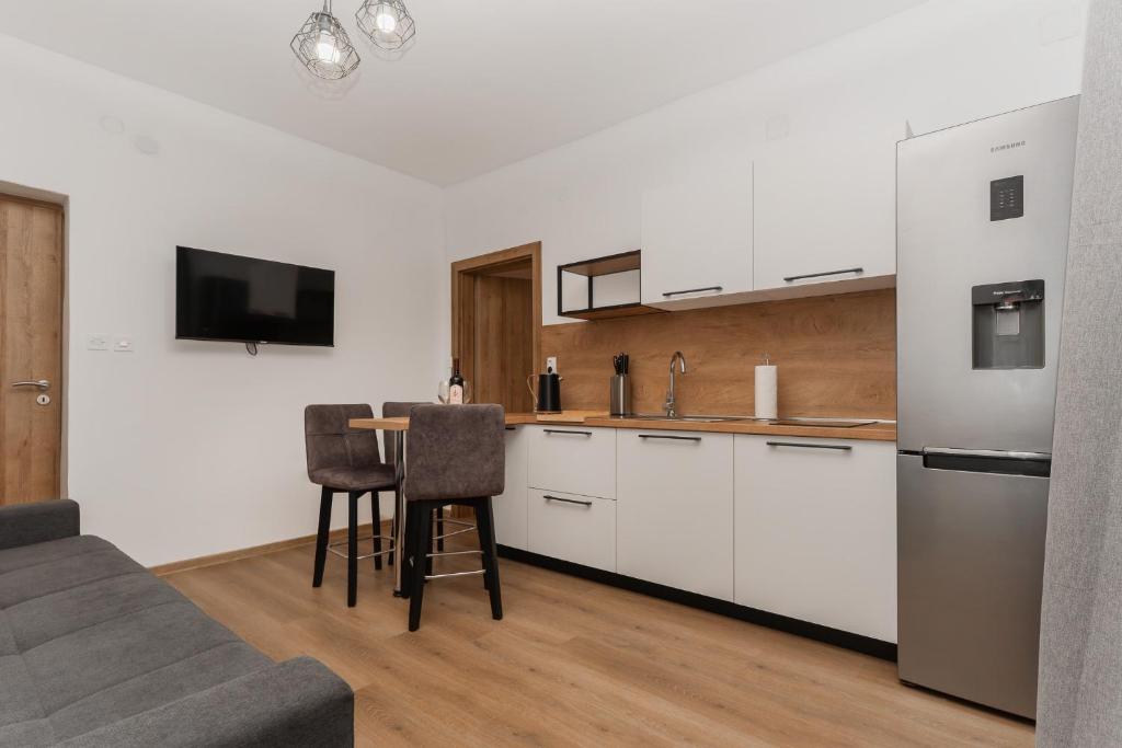 a kitchen with white cabinets and a table with chairs at Apartamenty U Dragana in Kaštela