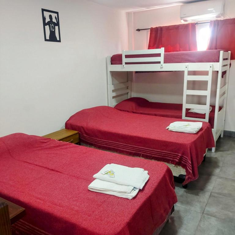 two bunk beds in a room with red sheets at Apart Mi Kaú in Catriel