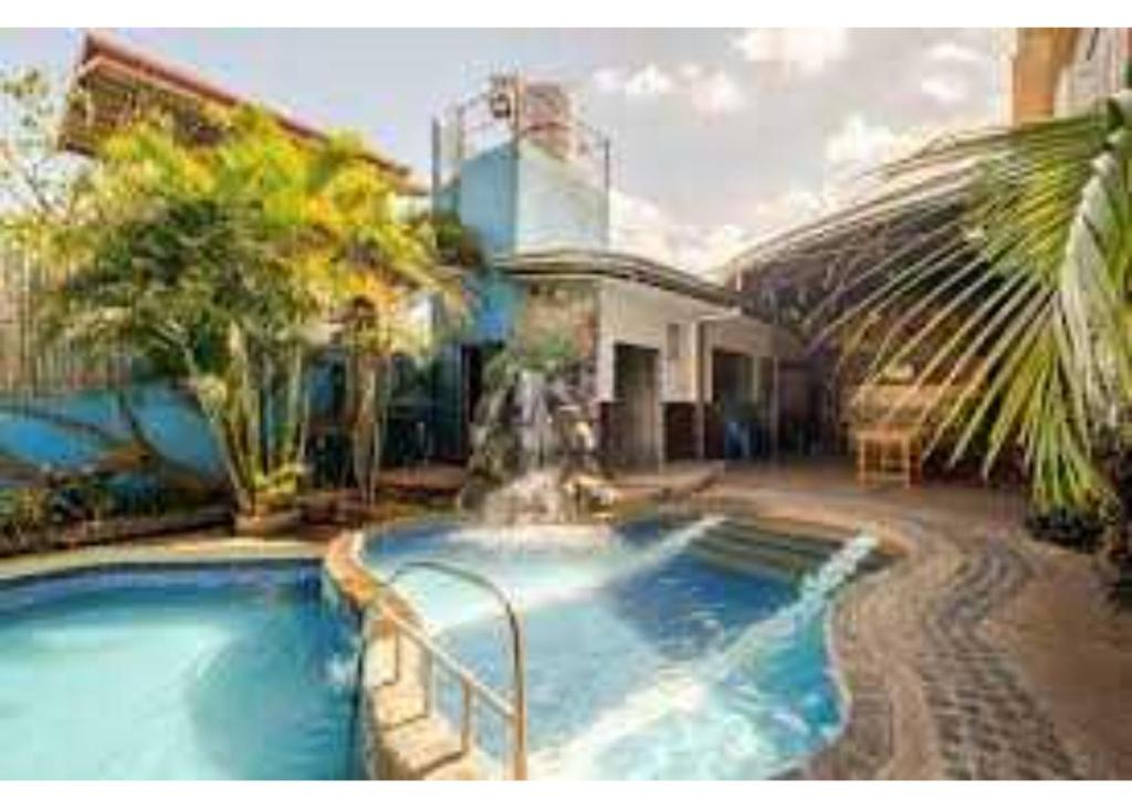 a swimming pool with a fountain in front of a house at OYO 1187 Rose And Ross Place Budget Hotel And Private Resort in Kabaong