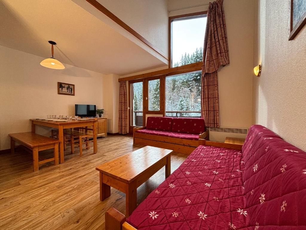een woonkamer met een rode bank en een tafel bij Résidence Saboia B54 Clés Blanches Courchevel in La Tania