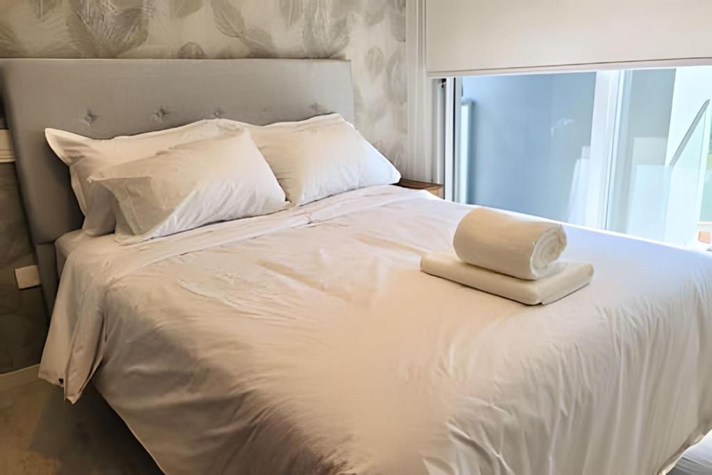 Una cama blanca con un libro encima. en Moderno y equipado, cerca del Paseo la Galeria, en Asunción