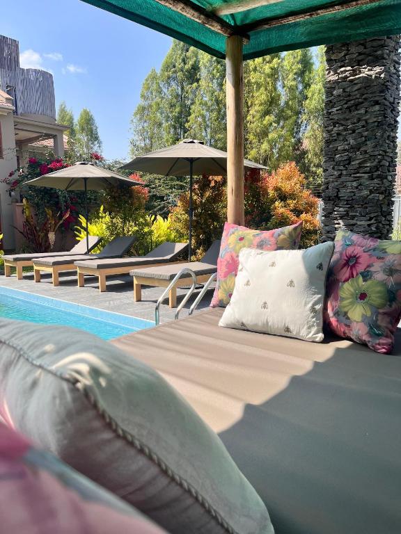 a bed with pillows and umbrellas next to a swimming pool at Marini Ndoto in Themi