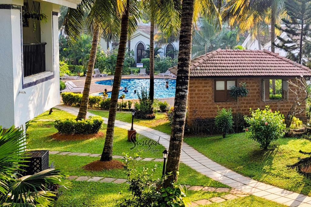ein Resort mit Swimmingpool und Palmen in der Unterkunft Susegad Suites Goa Apartments & Villas with Reserved Parking in Arpora