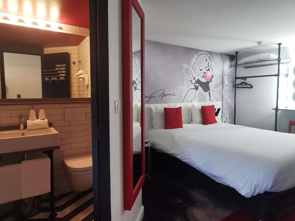 a bedroom with a bed and a bathroom with a sink at Ibis Styles Paris Saint Denis La Plaine in Saint-Denis