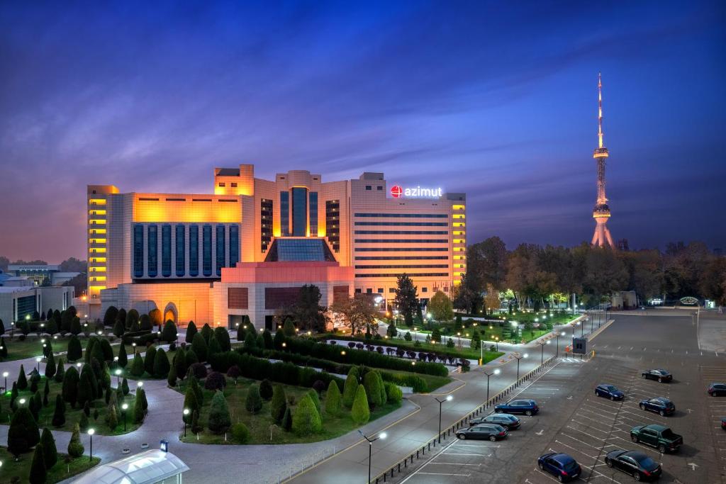 een groot gebouw met een parkeerplaats ervoor bij AZIMUT Grand Hotel Tashkent in Tasjkent