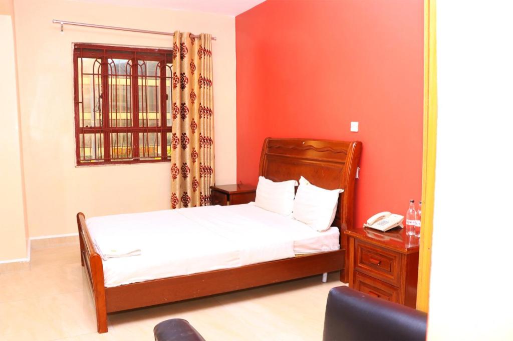 Un dormitorio con una cama y un escritorio con teléfono. en Geed Hotel, en Nairobi