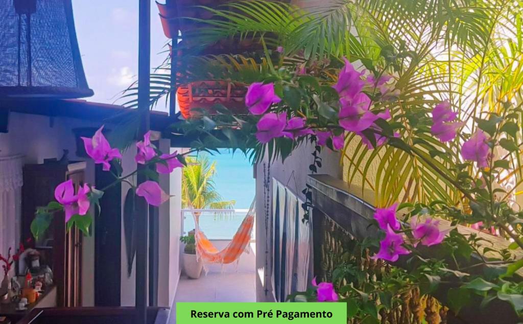 Un ramo de flores moradas en una pared con la playa. en Pousada Recanto da Família, en Natal