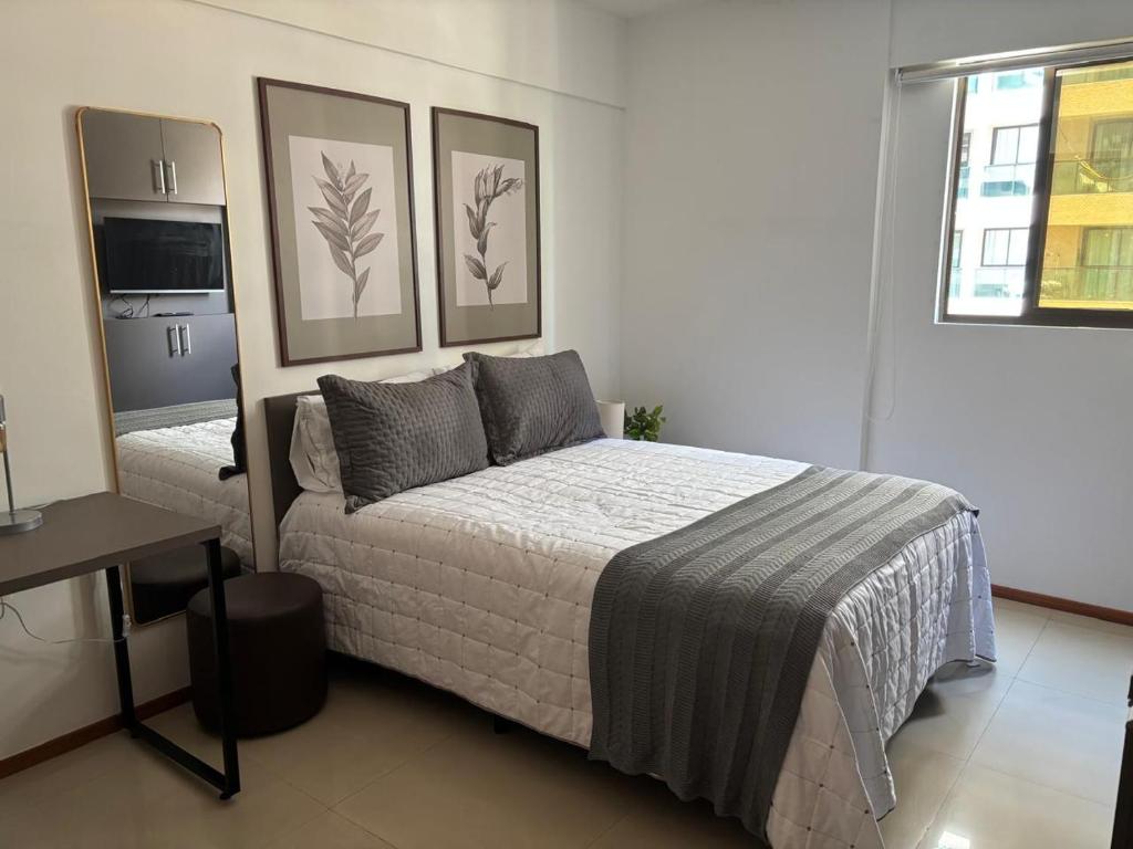 um quarto com uma cama e dois quadros na parede em Costa Nova VIP - Flat moderno e aconchegante em Ponta Verde em Maceió