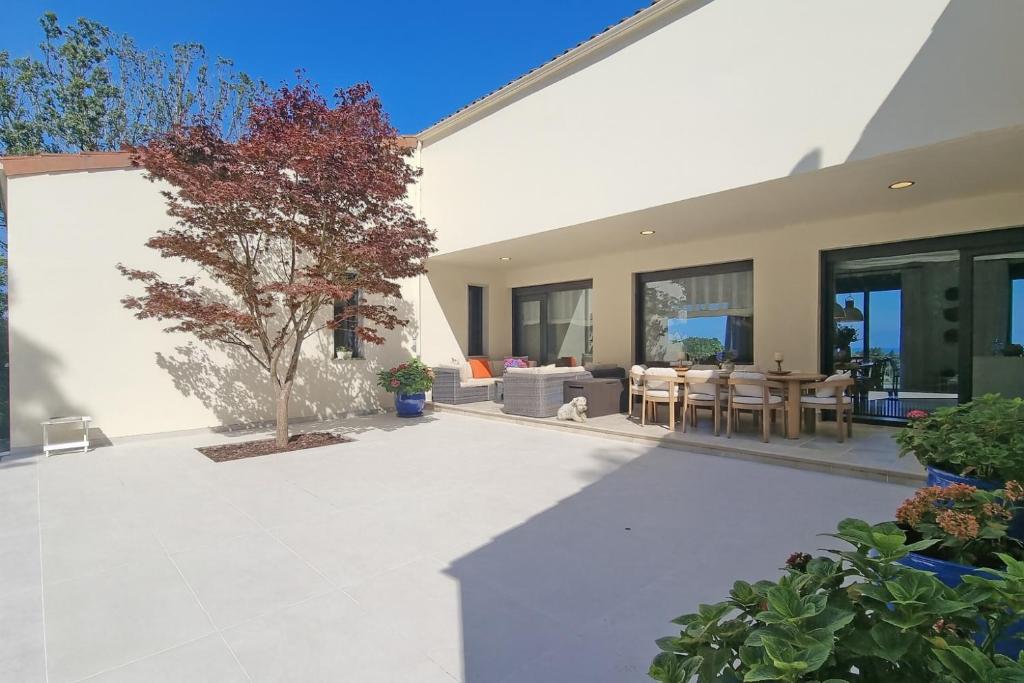 ein Haus mit einer Terrasse mit einem Baum im Hof in der Unterkunft Villa Las Encinas - Calidad y Confort en Llanes in Cuerres