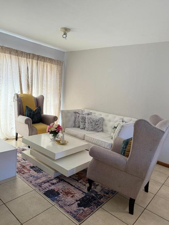 a living room with a couch and a table and chairs at Kloppenheim Sectional Lifestyle Complex in Ellisras