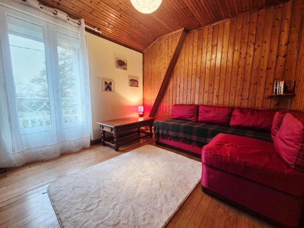 a living room with a red couch and a table at La maison d'à côté in Pluherlin