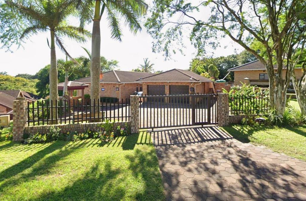 Lolly's Piece of Home في خليج ريتشاردز: سور أمام منزل به أشجار نخيل