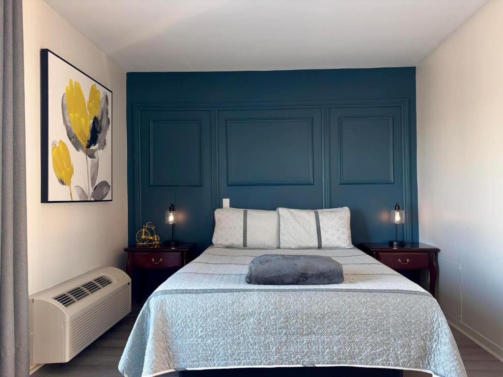 a bedroom with a bed with a blue wall at Motel le Point de Vue in La Malbaie