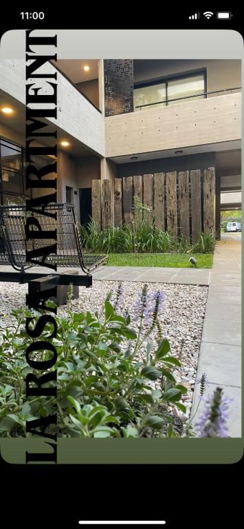 a building with a bench in front of a garden at La Rosa Apartment in Adrogué