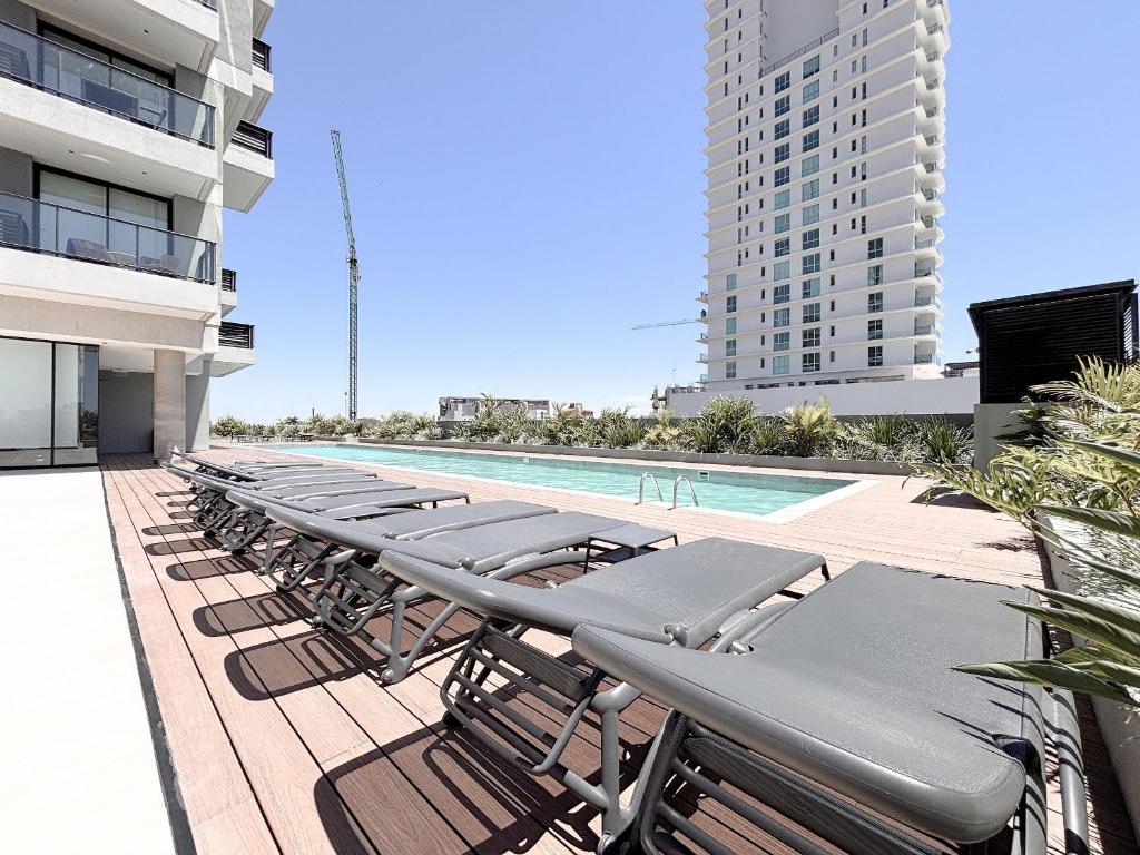 a row of lounge chairs and a swimming pool on a building at Dpto con piscina a pasos del Shopping del Sol in Asuncion