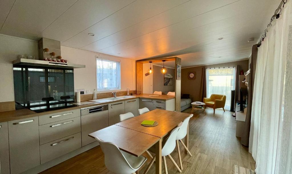 Una cocina con una mesa de madera y un comedor. en Charming ecolodge with heated pool all year round, en Les Mathes