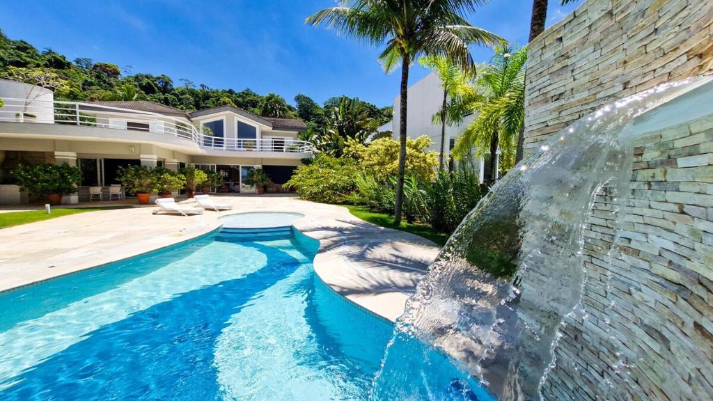 una piscina frente a una casa con una fuente en Mansão Pé na Areia no Condomínio Cocanha, en Água Boa