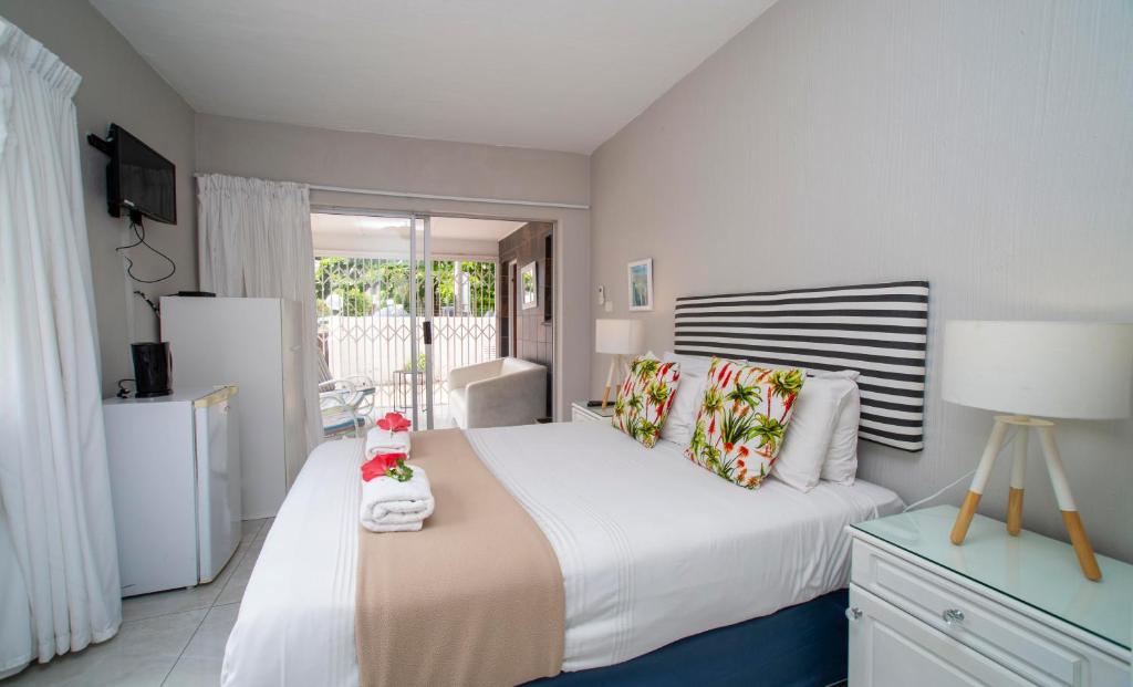 a bedroom with a white bed and a refrigerator at 1 Seabreeze Cottage in Durban