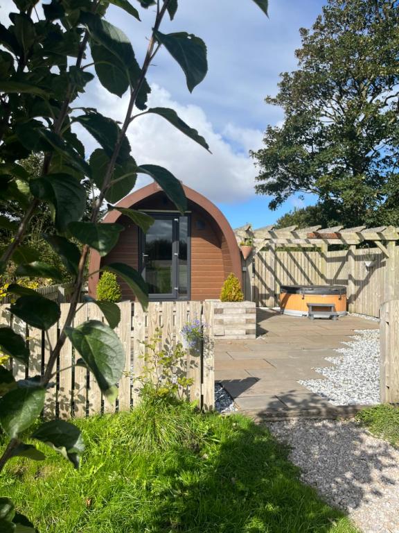 Mill House Farm Pods - Lapwing Lodge في Pilling: منزل صغير مع سور خشبي في ساحة