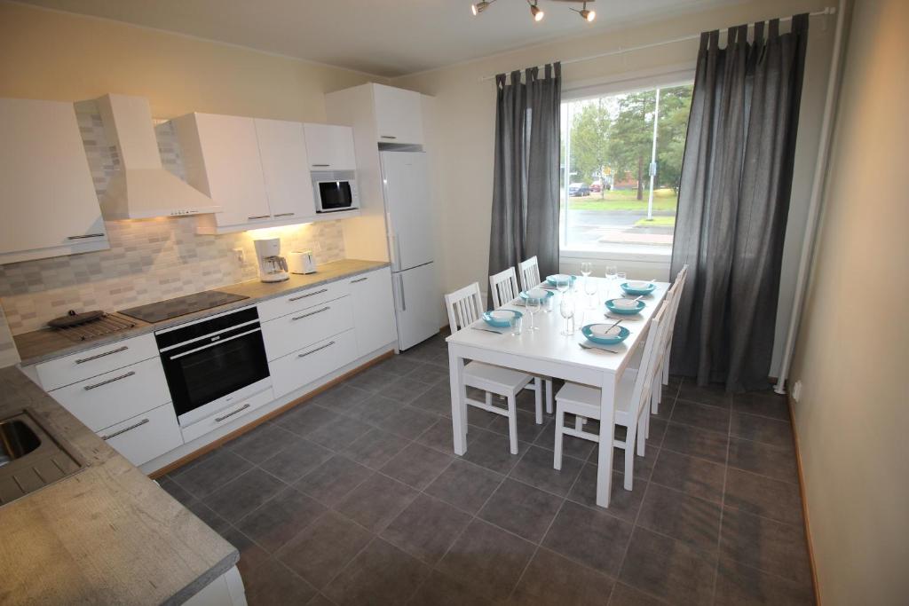 ロヴァニエミにあるHotel Aakenus Apartment Koskiのキッチン(白いテーブル、白いキャビネット付)