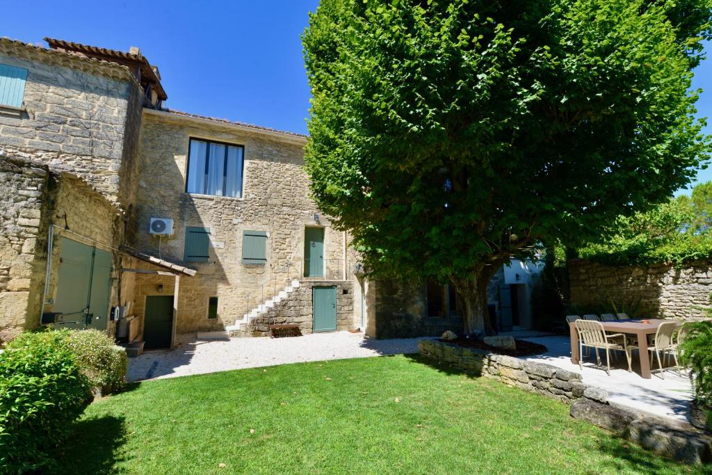 an old stone house with a tree and a yard at Le Clos Saint-Sif, 8 pers, clim, piscine chauffée in Saint-Siffret