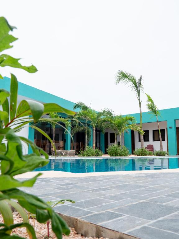 a swimming pool in front of a building with palm trees at Doña Dinde Vacacional in Punta Cana