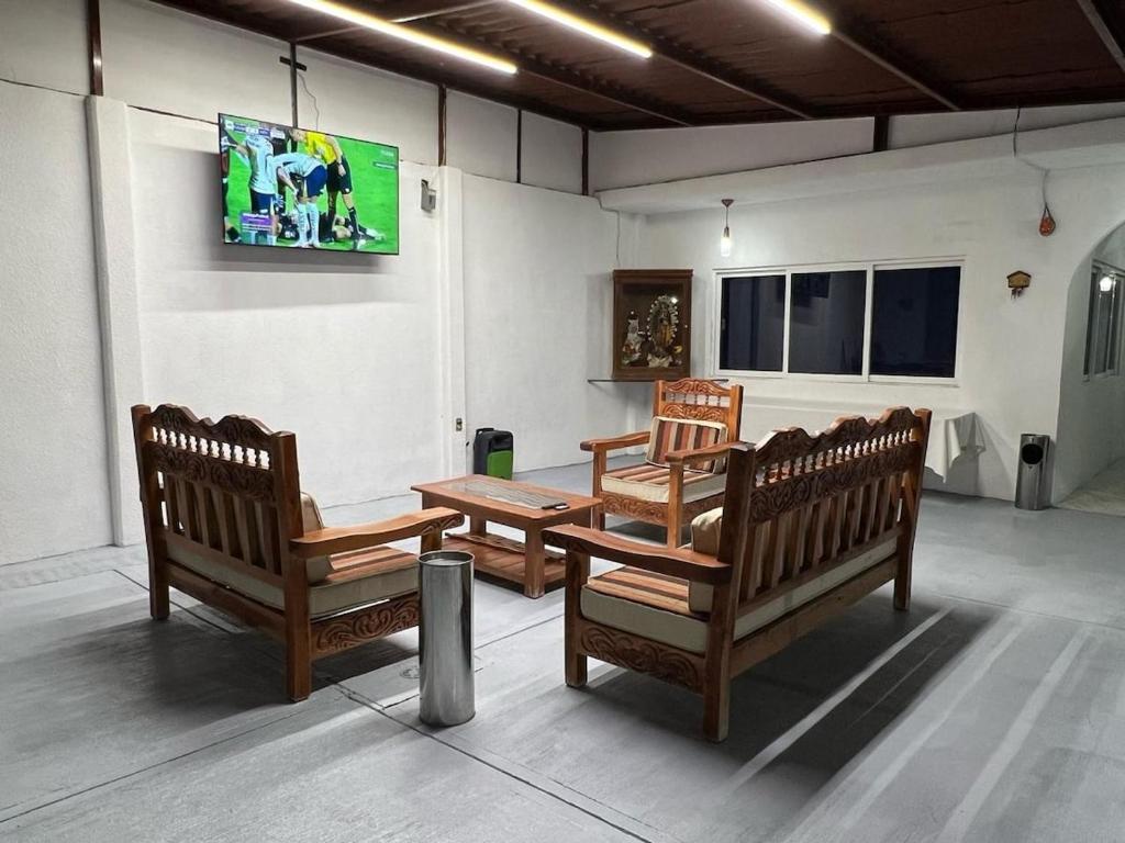 a room with three wooden benches and a tv at Casa en Cuautla, Morelos 
