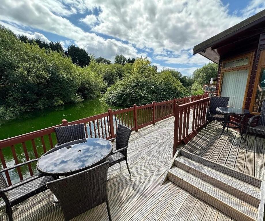 a patio with a table and chairs on a deck at Kingfisher Cosy Lakeside Lodge in Carnforth