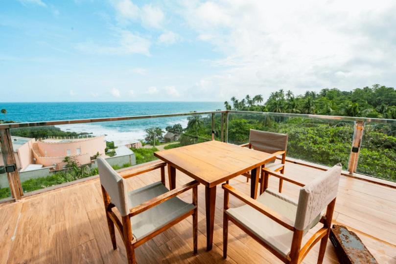 Mazarine Surf Suites- Hiriketiya في Nilwella: طاولة وكراسي خشبية على شرفة مع المحيط