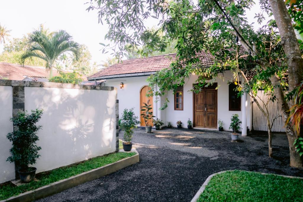 a white house with a fence and trees at Ninety Four Plus Madiha in Matara