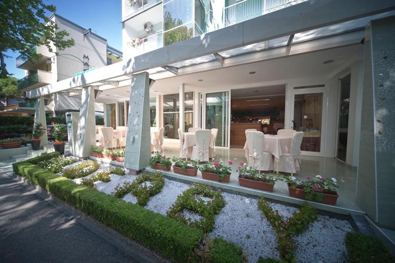 a house with white chairs and tables and flowers at Hotel Derby in Riccione