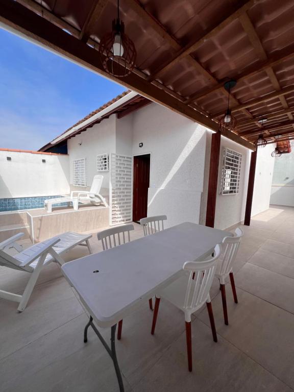 Una mesa blanca y sillas en un patio. en Casa Aconchegante em Itanhaem- Piscina e Churrasqueira 10 pessoas, en Itanhaém