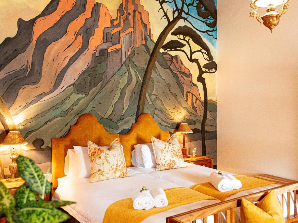 een slaapkamer met 2 bedden en een schilderij aan de muur bij Far Far Away Guesthouse in Graaff-Reinet