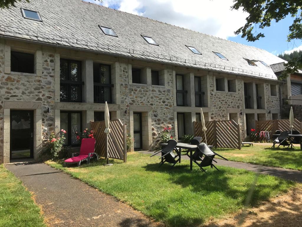 a building with chairs and a table in front of it at Gites et camping le Sédour in Riom-ès-Montagnes