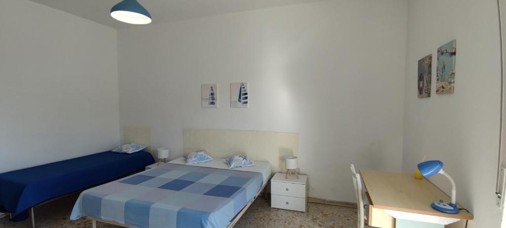 una piccola camera con letto blu e scrivania di Casa Vivì a Manfredonia