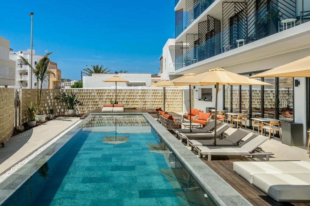 a swimming pool with chairs and umbrellas on a building at Hotel Vibra Yamm Urban - Adults only in San Antonio