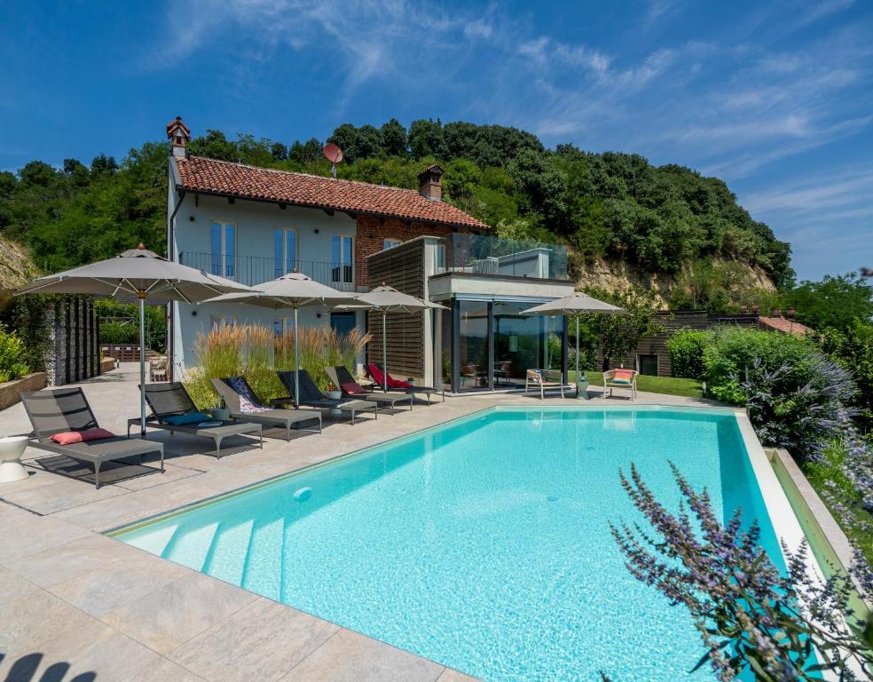 ein Swimmingpool mit Stühlen und Sonnenschirmen neben einem Haus in der Unterkunft Relais Casa Clara in Montaldo Roero
