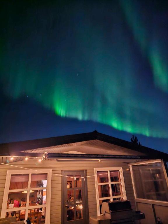 a house with the northern lights in the sky at Hreiðrið cozy cabin in the countryside in Selfoss