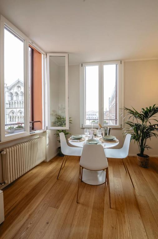 a living room with a table and chairs and windows at PrimeLoft Cathedral-Panoramic Suite in Ferrara