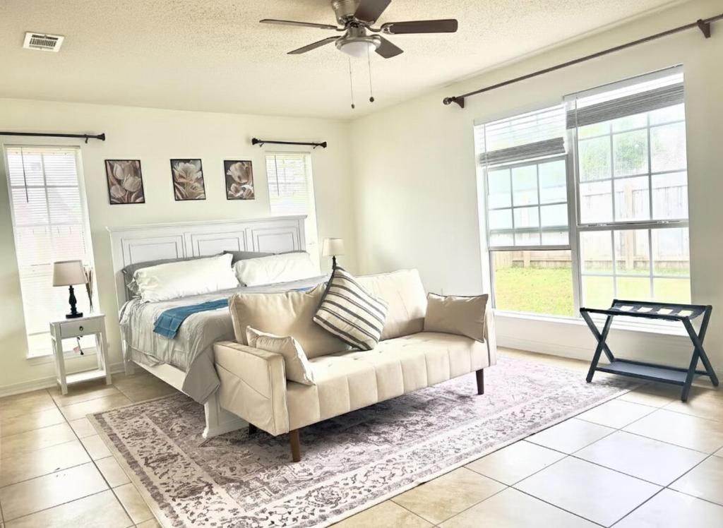a bedroom with a bed and a couch and windows at Cozy Private Room in Milton near Beaches in Milton
