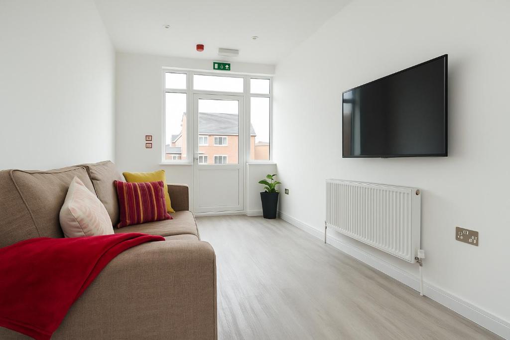 een woonkamer met een bank en een flatscreen-tv bij Rehoboth Housing in Cranford