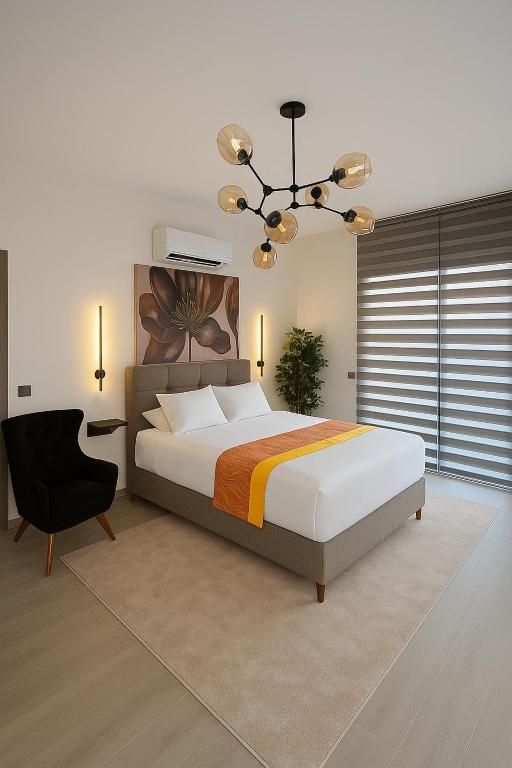 a bedroom with a large bed and a black chair at Elegant Ephesus Suites - Hadrian in Selçuk