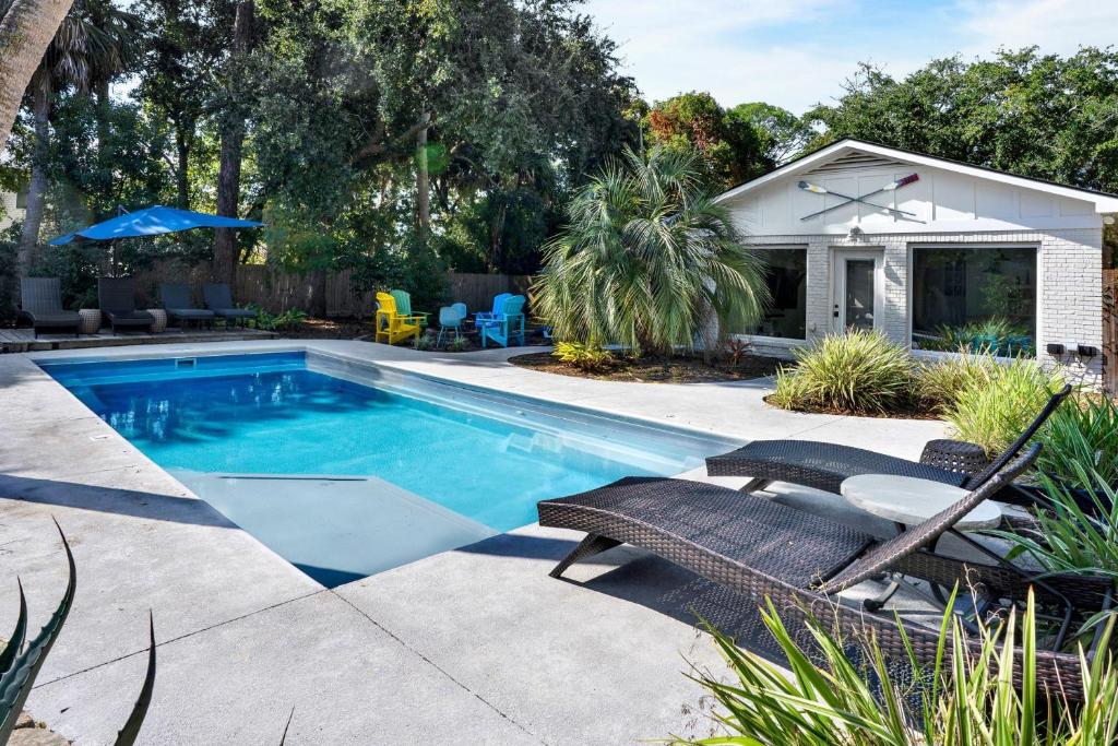 a swimming pool in a yard with chairs and a house at The Oar House in Tybee Island