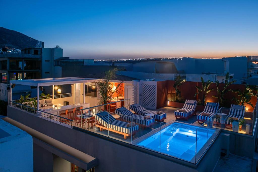 a rooftop patio with chairs and a swimming pool at night at Nissos Home by Prime Stay in Hersonissos