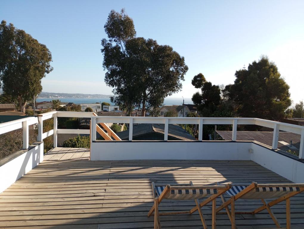 dois bancos em um deck de madeira com um parapeito em Oceana Suites en Algarrobo em San Antonio