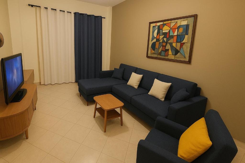 een woonkamer met een blauwe bank en een tv bij Aegean Helios Houses in Gennadi